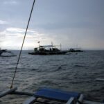 Tre bancabåtar för dykning förtöjda vid Monad Shoal under en grå gryningshimmel, sedda från däcket på en annan båt