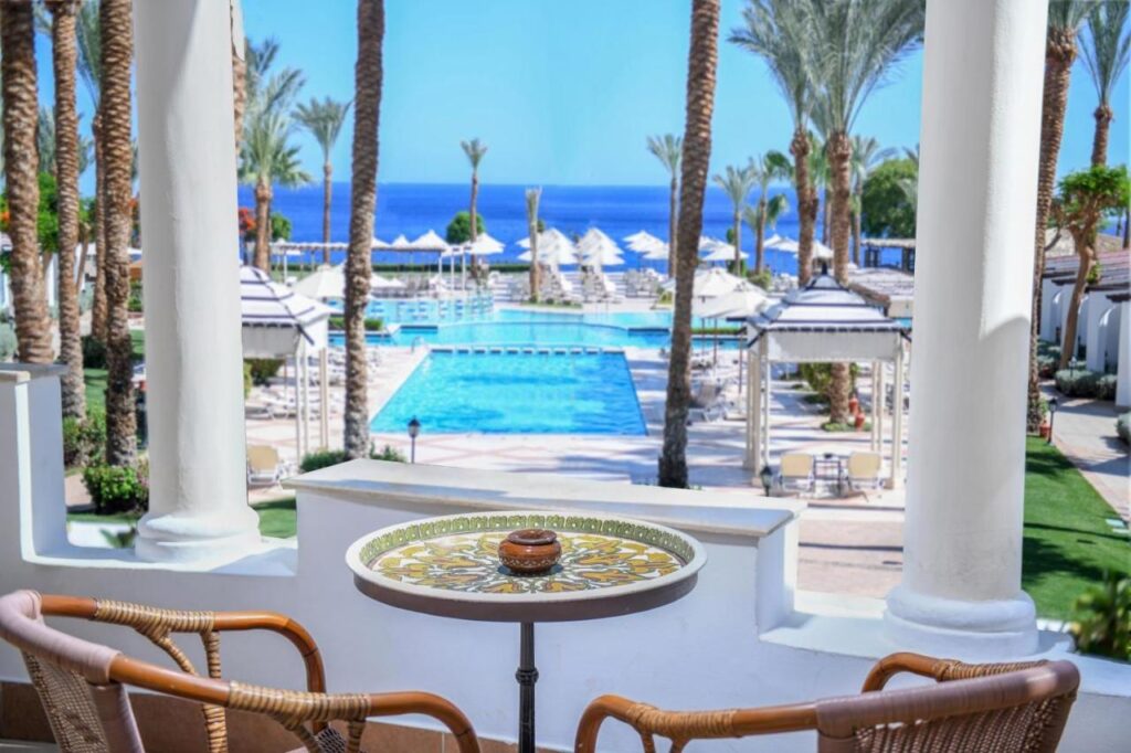 Utsikten från en terrass på JAZ Fanara Resort över poolerna, palmerna och Röda havet