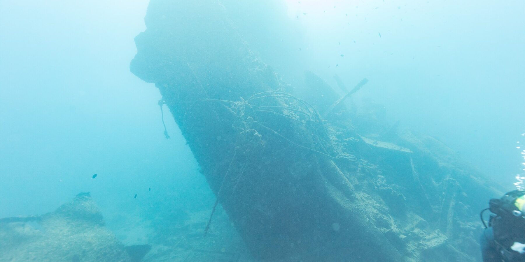 Den brutna aktern på Thistlegorm reser sig snett i det blå, med en dykare till höger