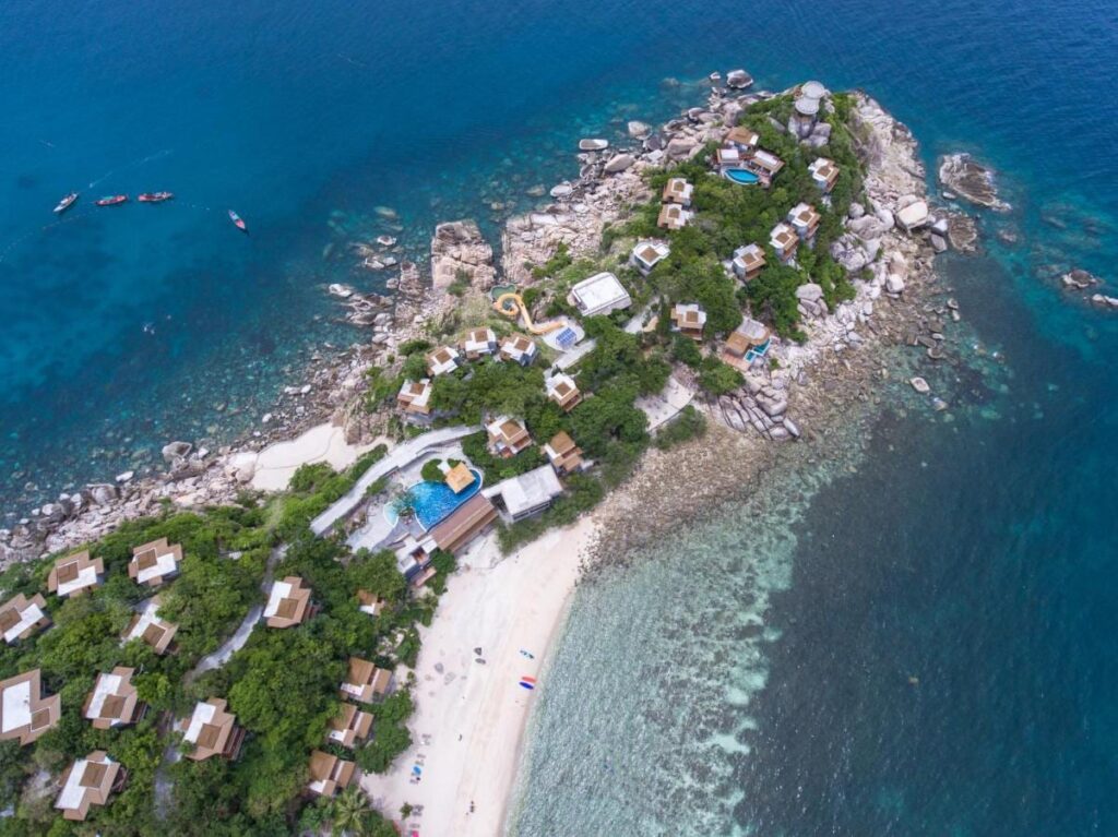Flygbild över Sai Daeng Resort, med bungalower på en klippudde, pooler och en sandstrand