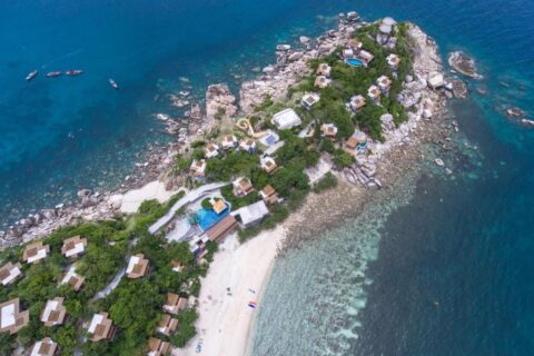Flygbild över Sai Daeng Resort, med bungalower på en klippudde, pooler och en sandstrand