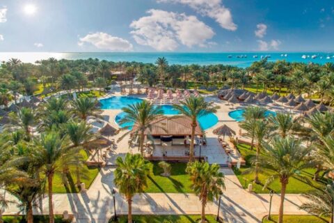 Flygbild över Siva Grand Beach, med pooler bland palmerna och Röda havet med båtar för ankar