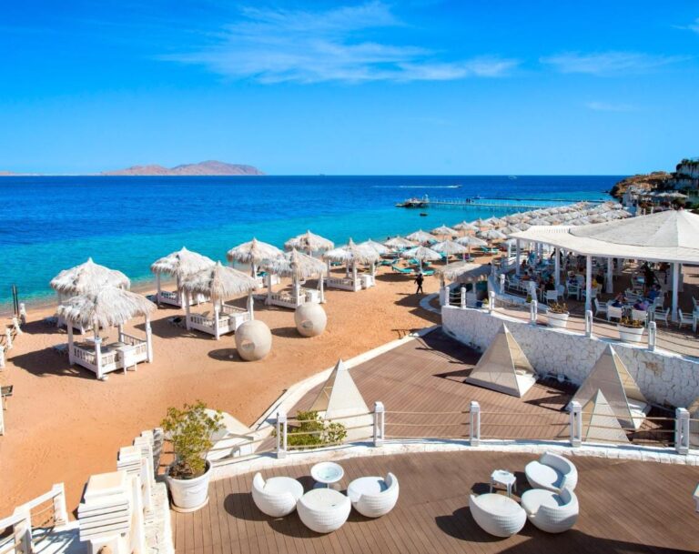 Stranden på Sunrise Arabian Beach Resort, med halmparasoller och brygga, mitt emot ön Tiran